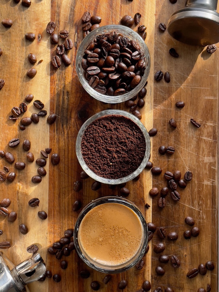 Coffee beans and ground coffee in bowls on a wooden table