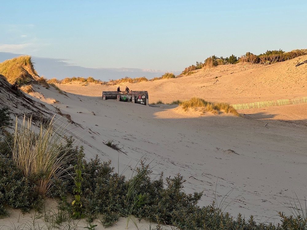 Dunes at dusk with a low building on the ridge